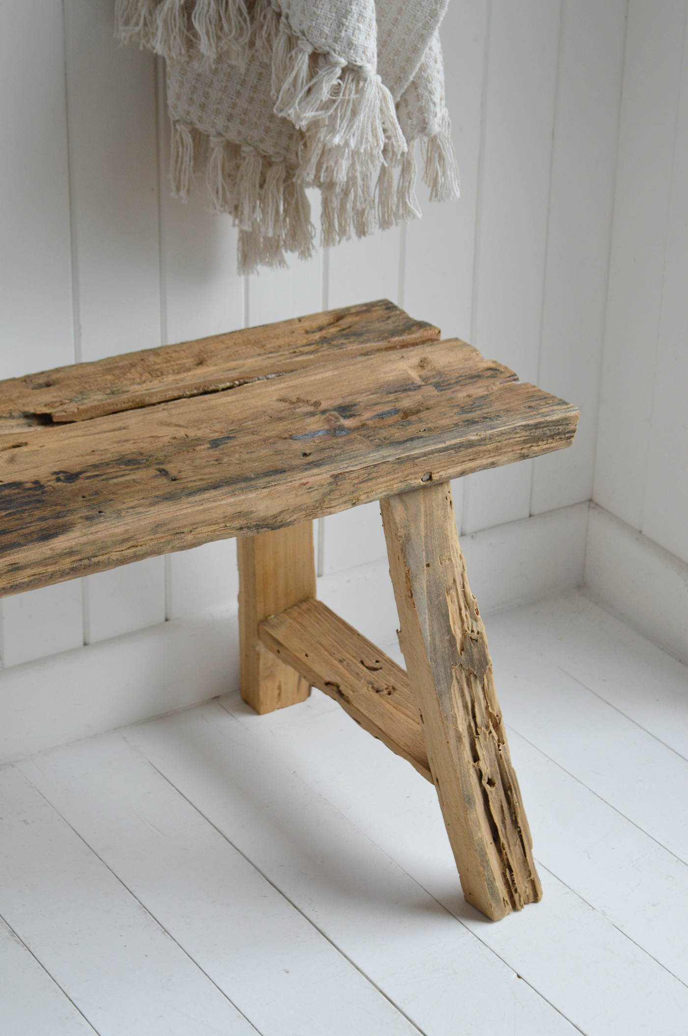 Natural driftwood bench on white wooden floor in coastal home setting