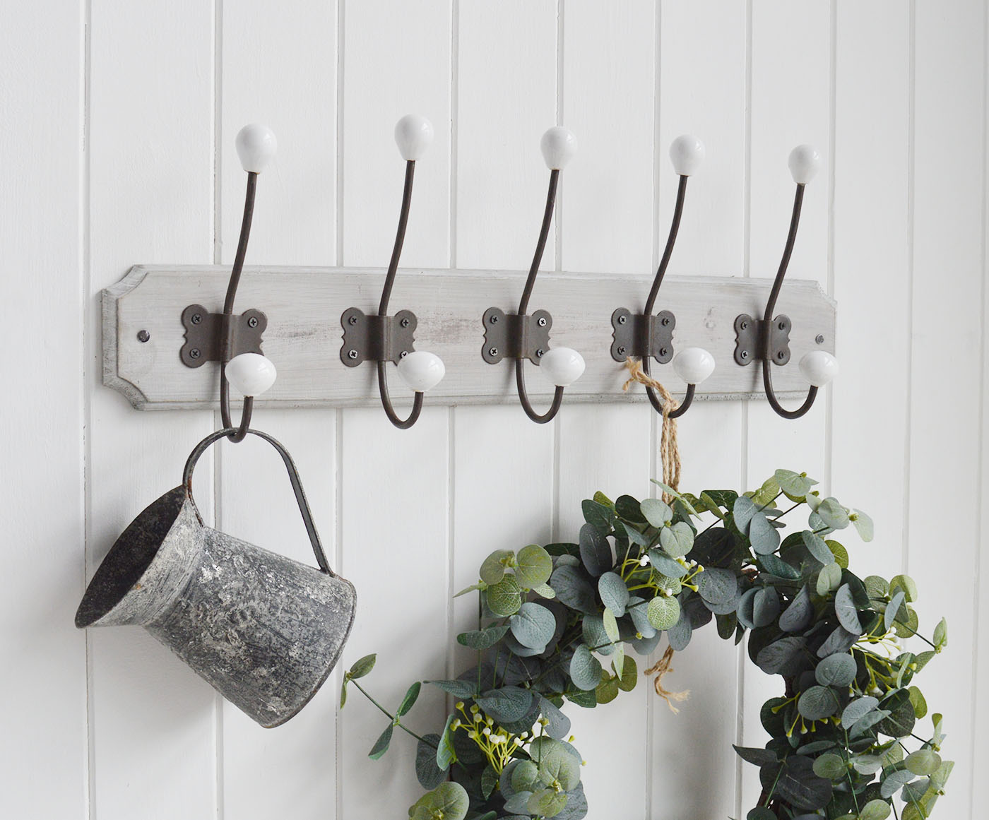 A wall mounted coat rack with five aged metal double hooks with porcelain ends on a rustic grey washed wooden backing.

The Pawtucket Range is a range of furniture and home decor made from grey wash reclaimed wood for an authentic distressed rustic look