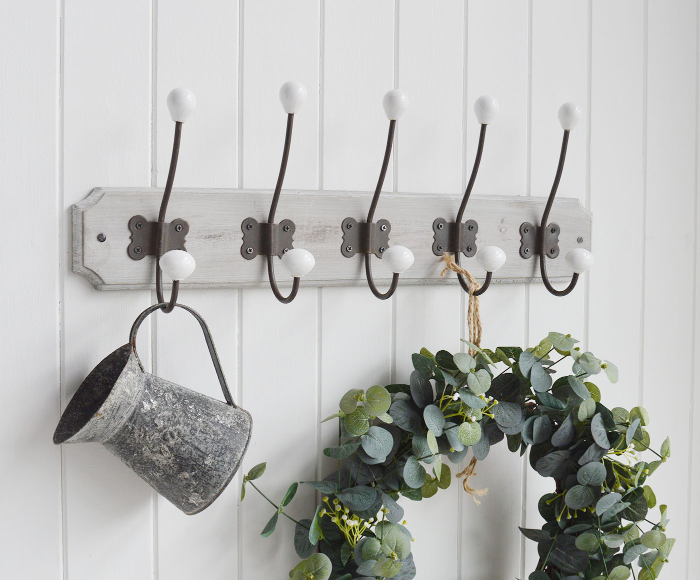 A wall mounted coat rack with five aged metal double hooks with porcelain ends on a rustic grey washed wooden backing.

The Pawtucket Range is a range of furniture and home decor made from grey wash reclaimed wood for an authentic distressed rustic look