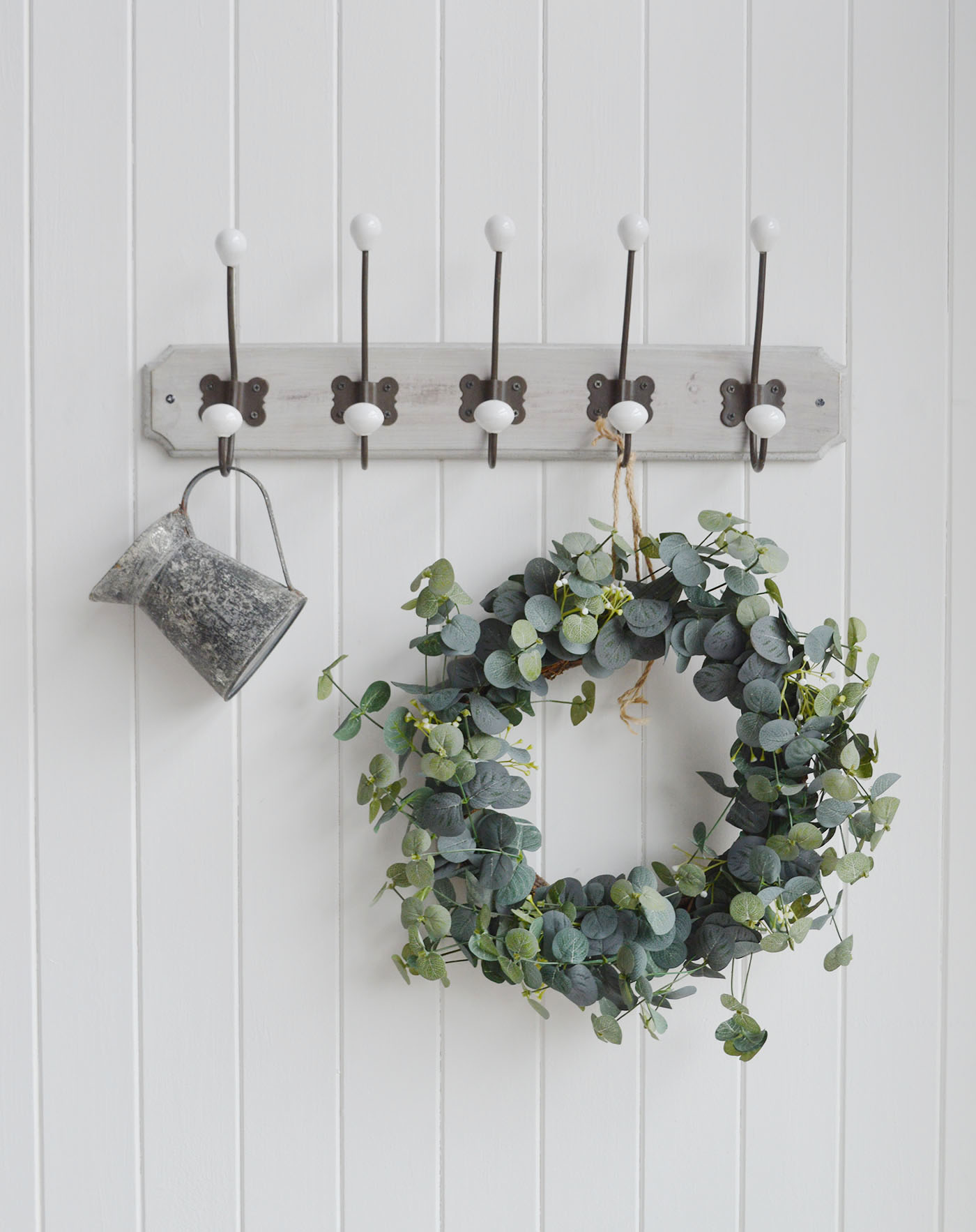 A wall mounted coat rack with three aged metal double hooks with porcelain ends on a rustic grey washed wooden backing.

The Pawtucket Range is a range of furniture and home decor made from grey wash reclaimed wood for an authentic distressed rustic look .