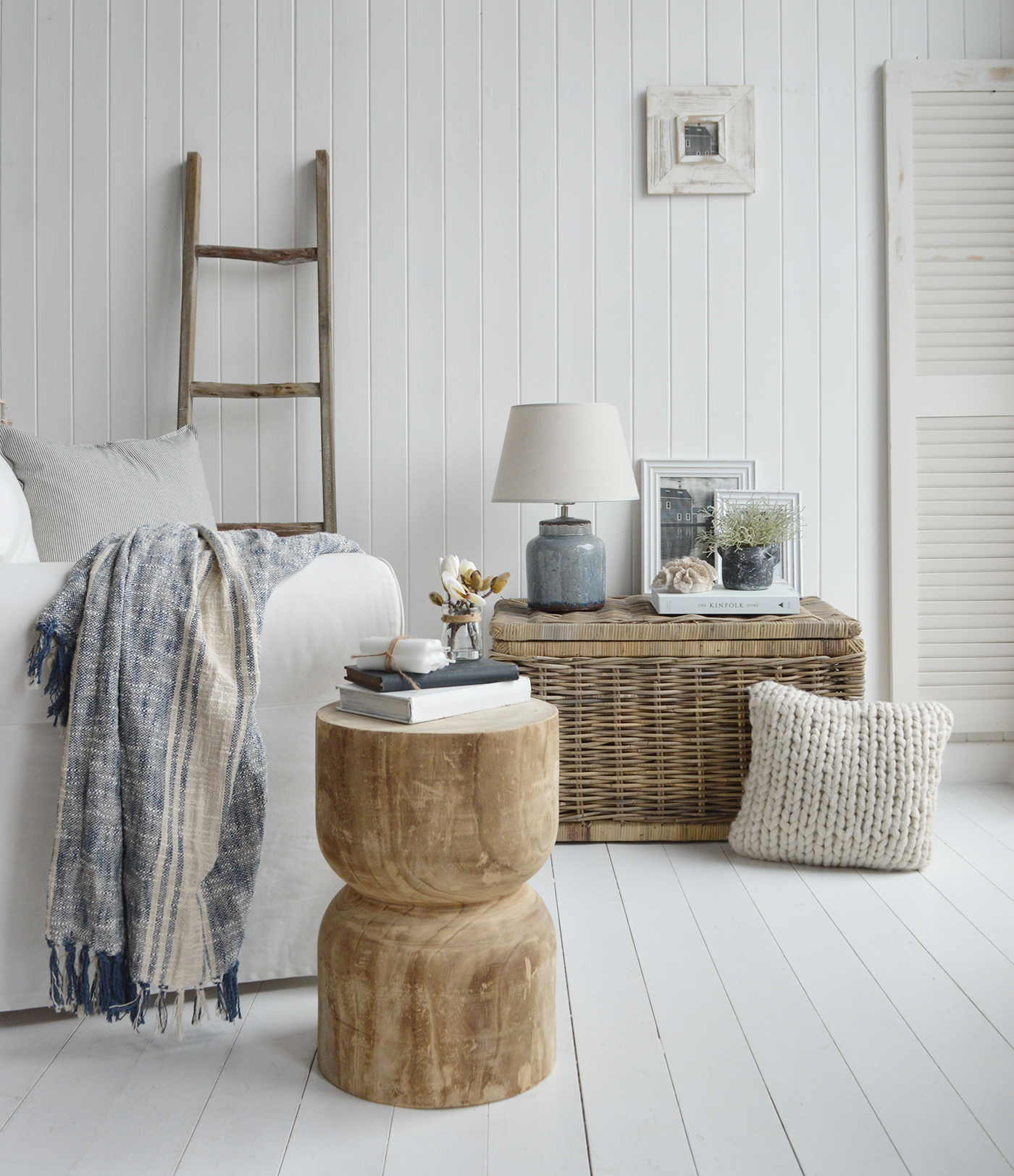 A modern farmhouse house or coastal living room in New England style. The Ascaot hand carved wooden table with the Blue Compton lamp on the Seaside storage table complemented with the blue and linen Hudson throw and lastley the driftwood blanket ladder