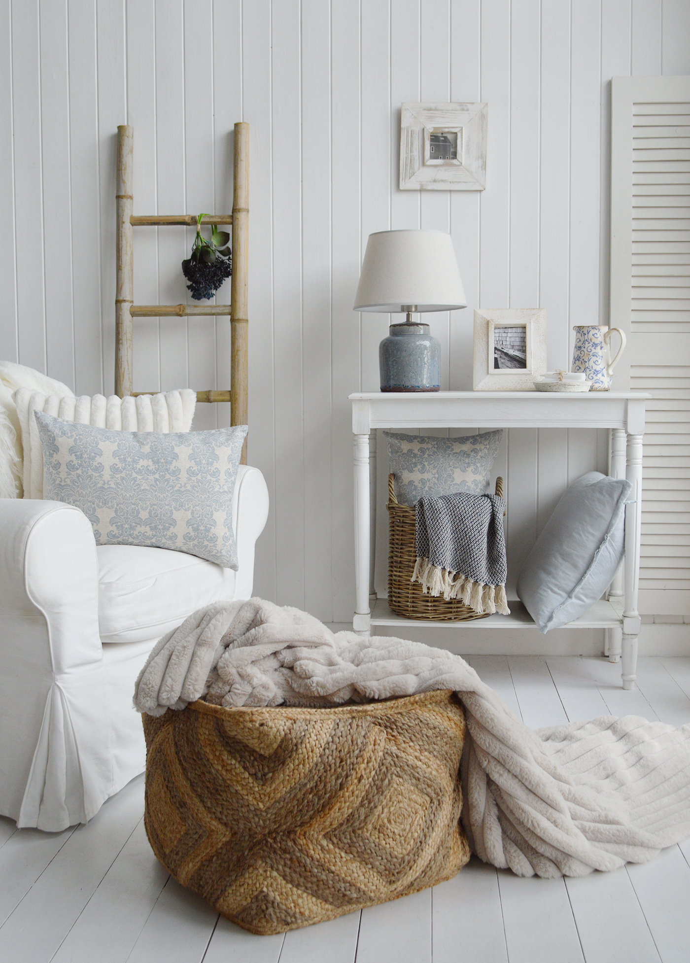 Coastal inspired Hamptons living room in blues and white with natural materials in the baskets and blanket ladder