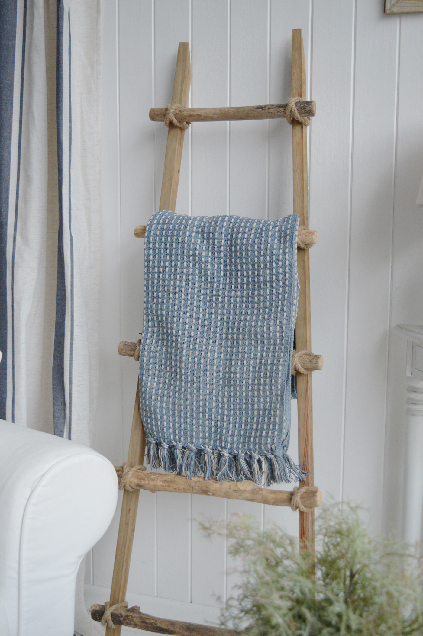 A blue and white throw adds colour and softness to the driftwood ladder.