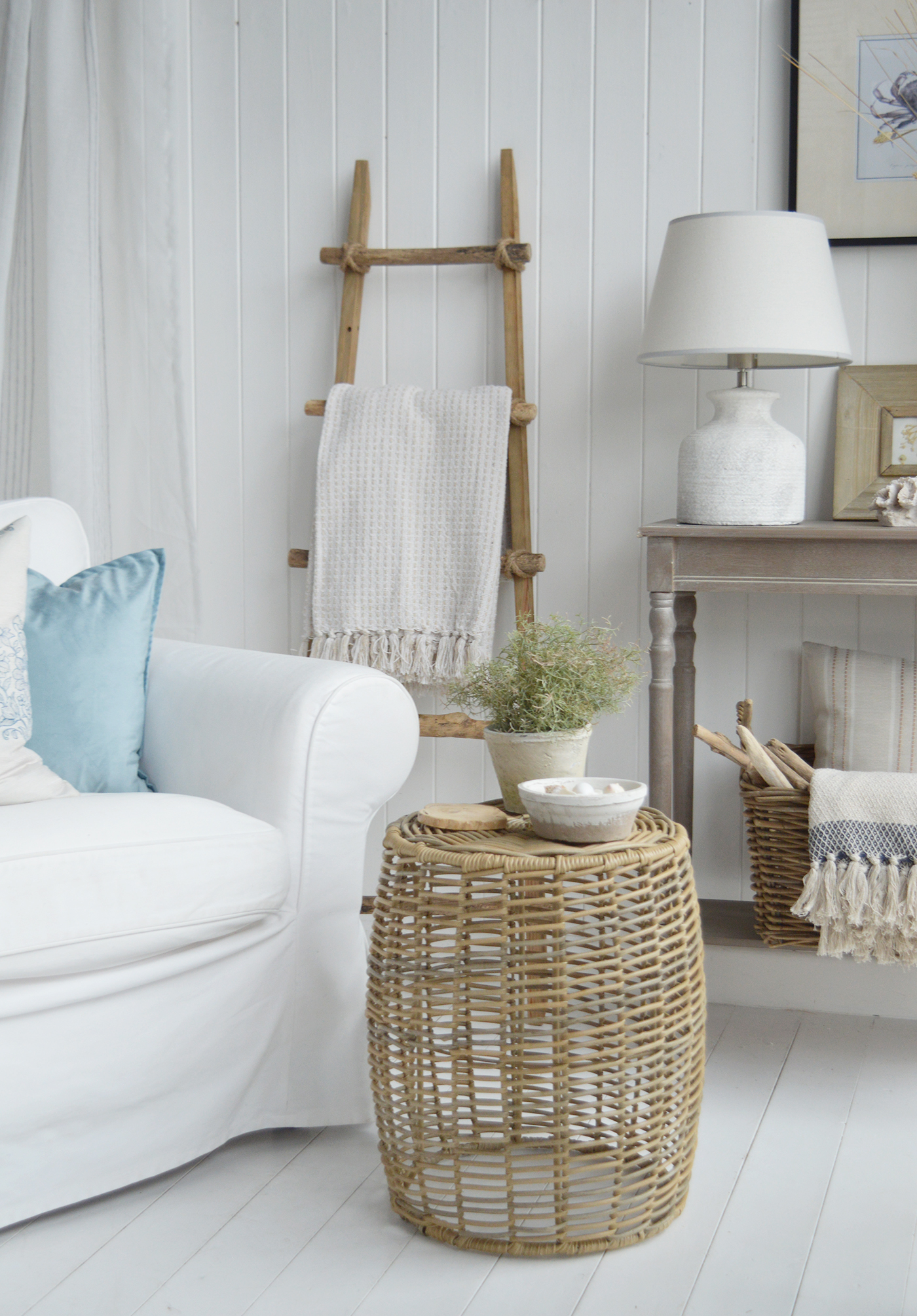 A white armchair, pale blue cushions and the woven Casco Bay side table bring soft colour and natural texture to this neutral coastal living room.