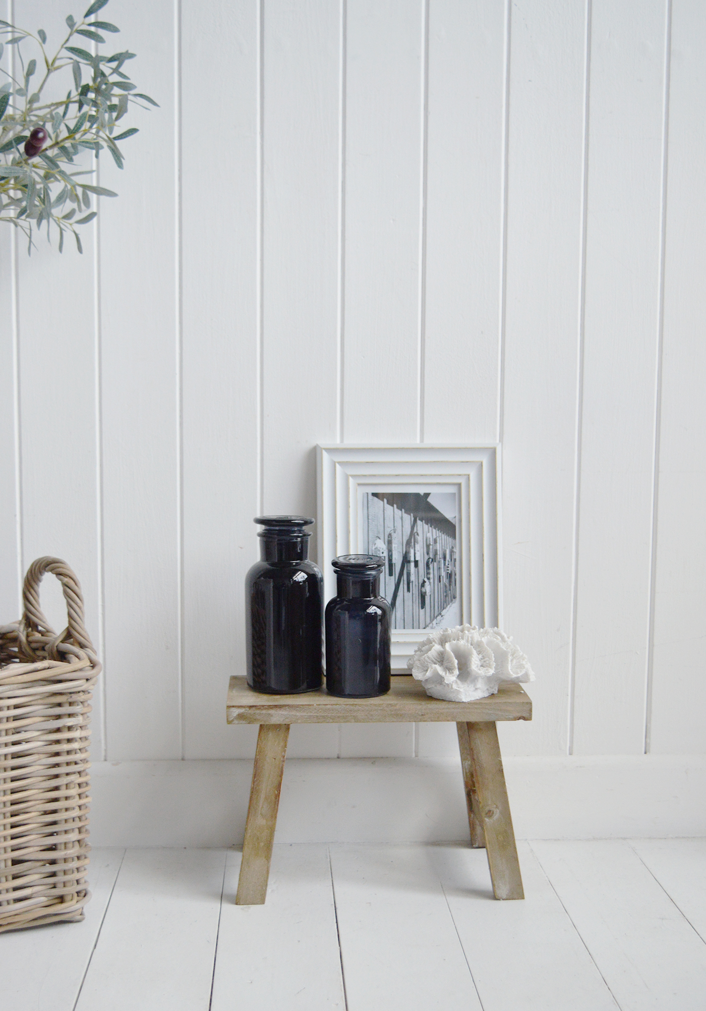 The Pawtucket small rustic wooden stool for home interiors. Styled with faux corak, apothecarf baootles and a photo frame for height