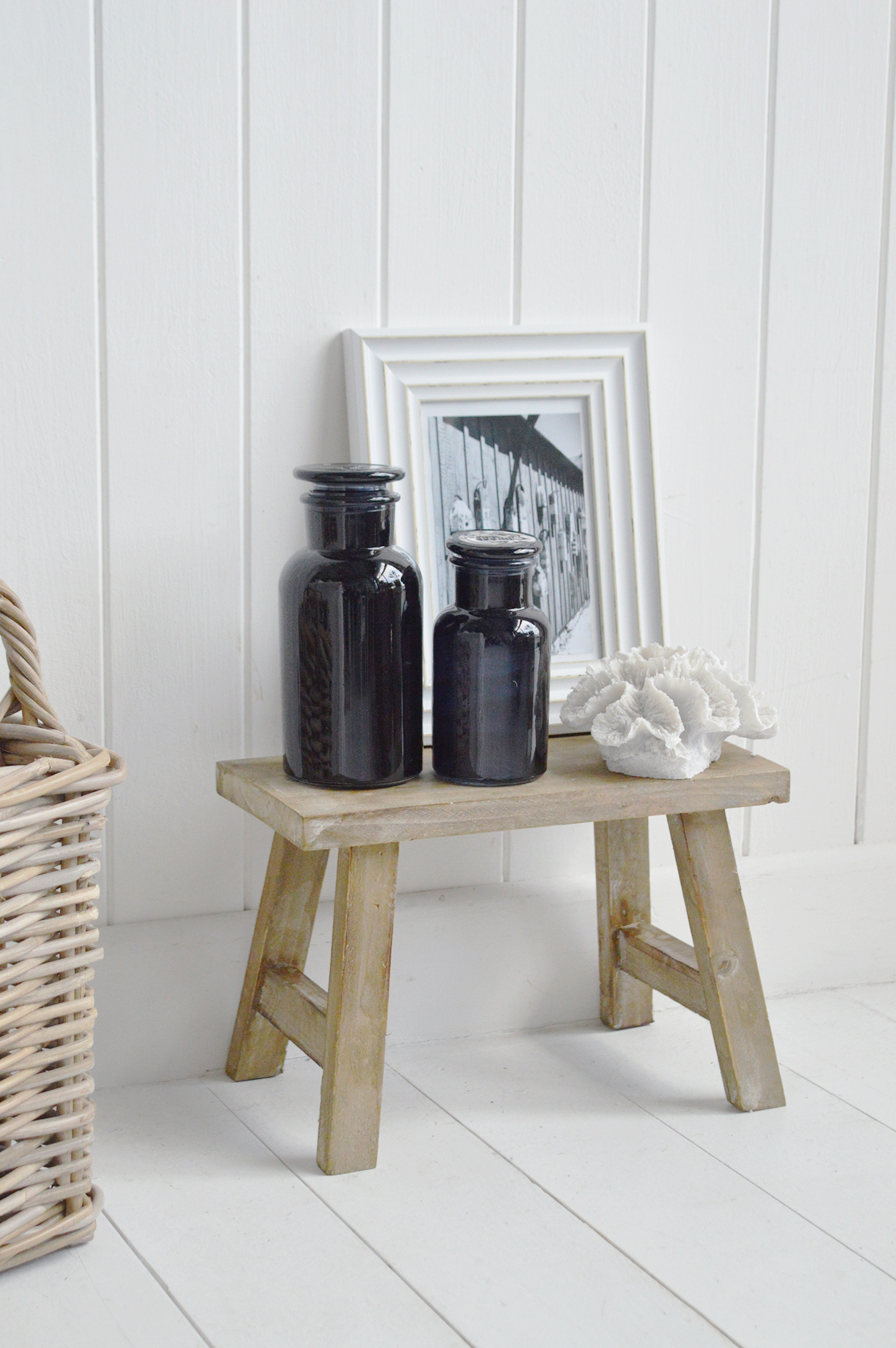 The Pawtucket rustic small wooden stool for home interiors. Styled with faux corak, apothecarf baootles and a photo frame for height