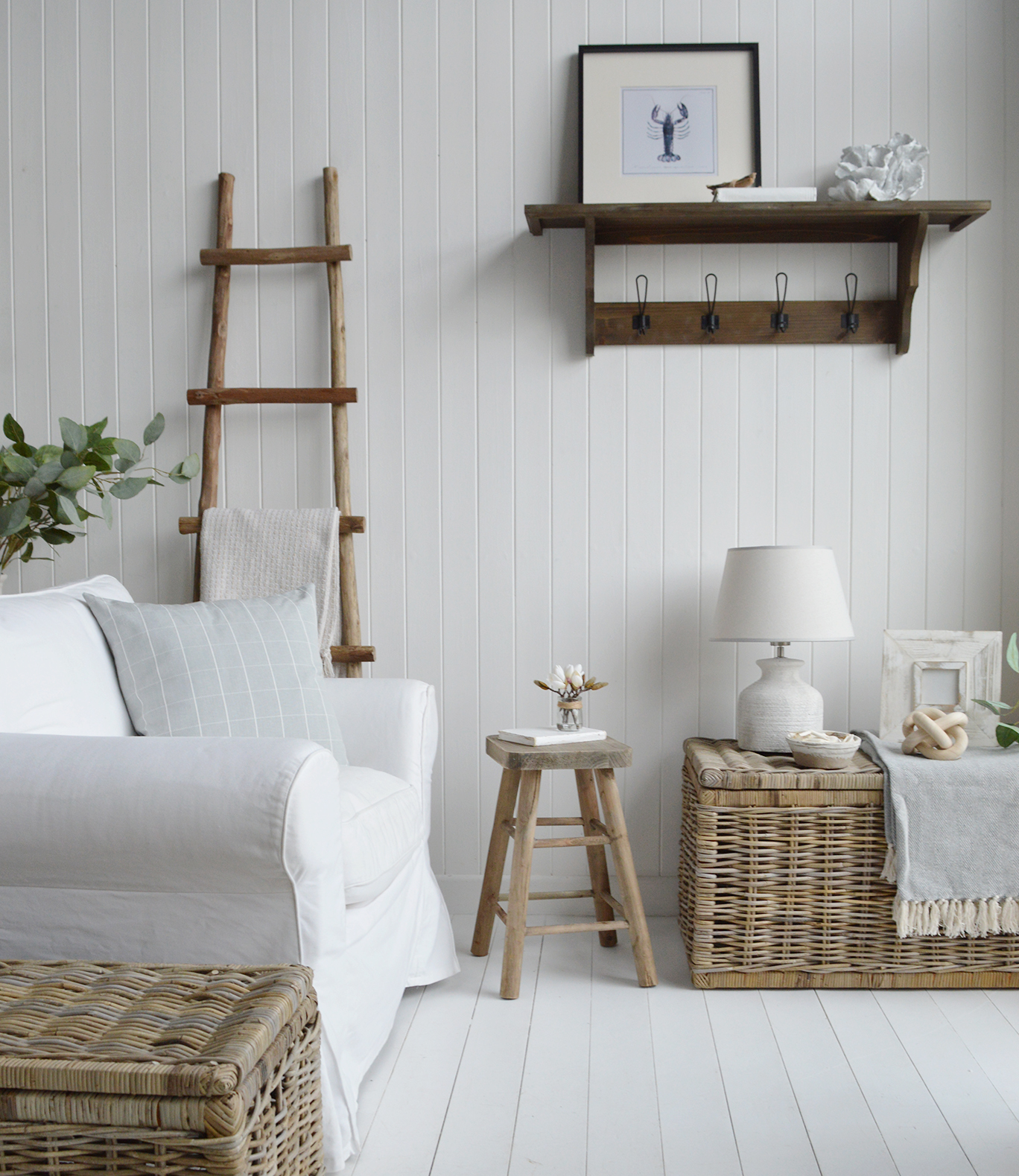 The wooden stool, worn smooth by years of salty air, serves as a charming makeshift table in the cozy beach house living room. Perched beside a sun-bleached couch, it holds a seashell-filled glass bowl and a steaming cup of coffee, completing the relaxed coastal vibe.