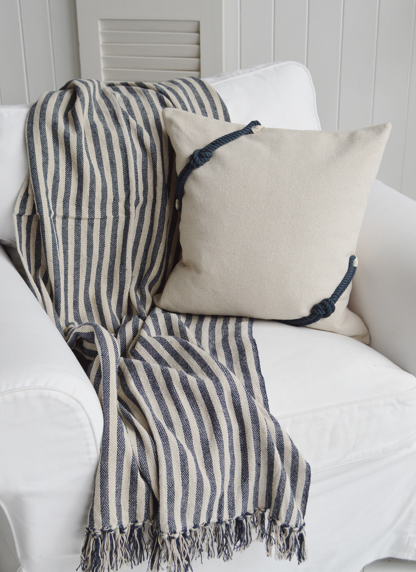 Coastal style cushion paired with a navy and natural stripe throw, styled in a light, beach-inspired interio
