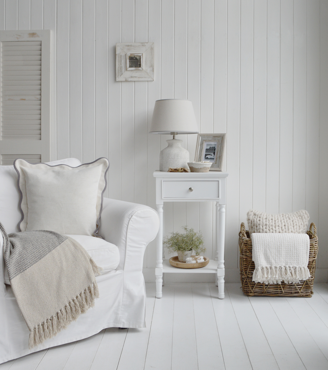 A serene neutral-toned coastal interior showcasing a white lamp table styled with beach-inspired decor, soft furnishings, and natural textures, creating a relaxed and elegant beach house atmosphere