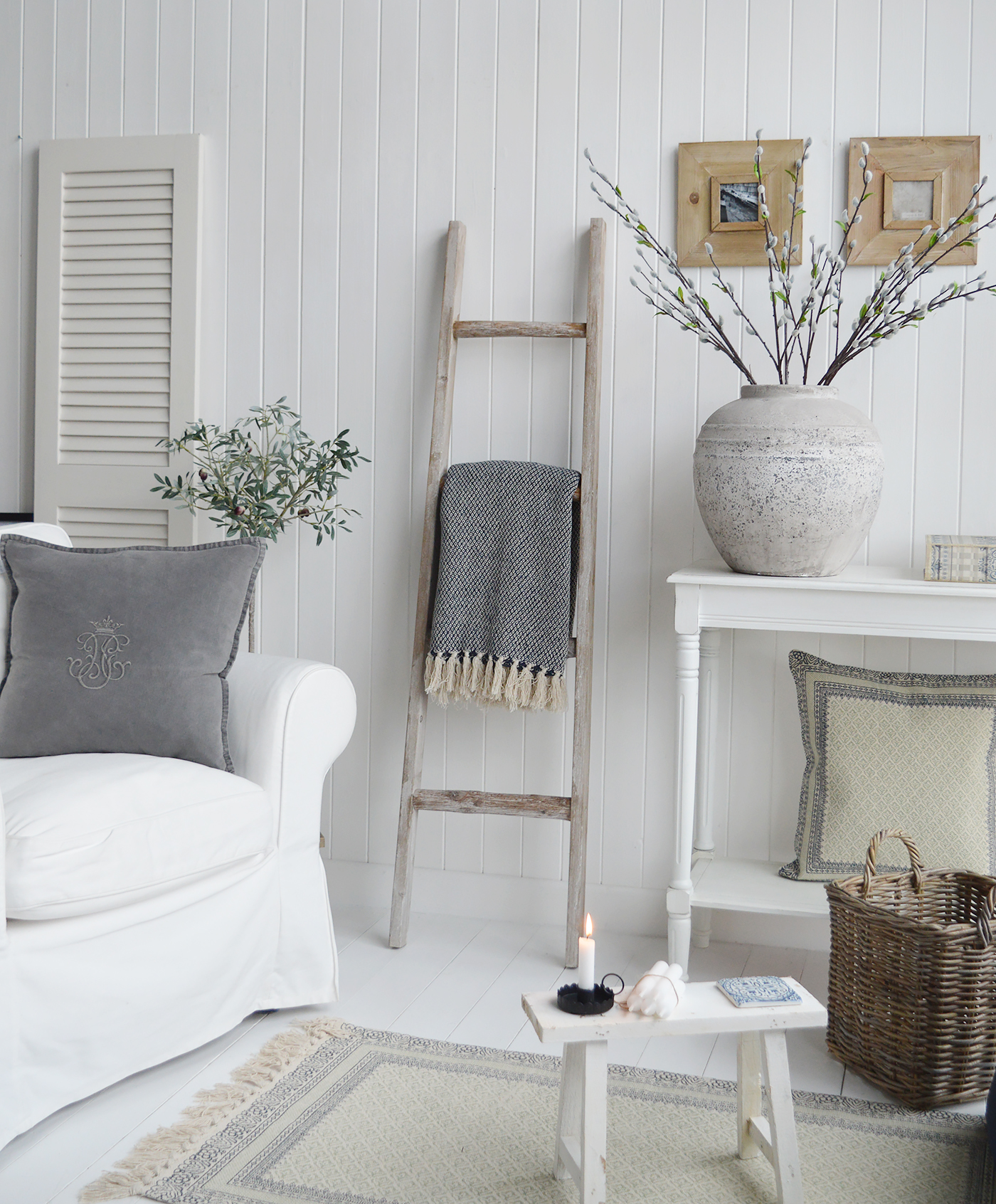 A new England style living room with blanket ladder , lots of cushions and a white console table with home decor accessories