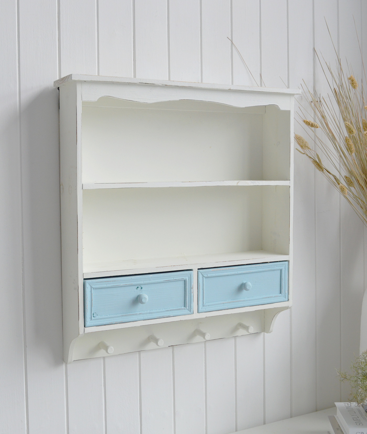 This distressed wall shelf features two display shelves, two storage drawers and four useful wooden hanging pegs.