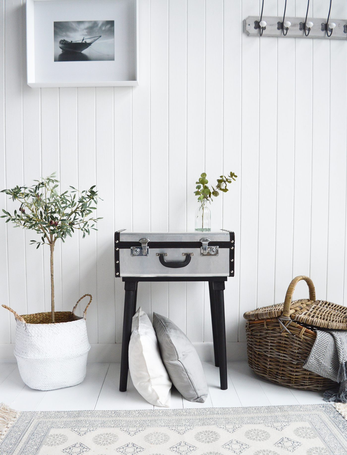 The Woodstock silver suitcase table.    A unique style of side table in the style of a vintage suitcase with lockable storage. Ideal as a bedside or lamp table in the living room or hallway.    Finished in a brushed slightly distressed silver metal, traditional lockable clasps, metal studding, black edging and black wooden legs