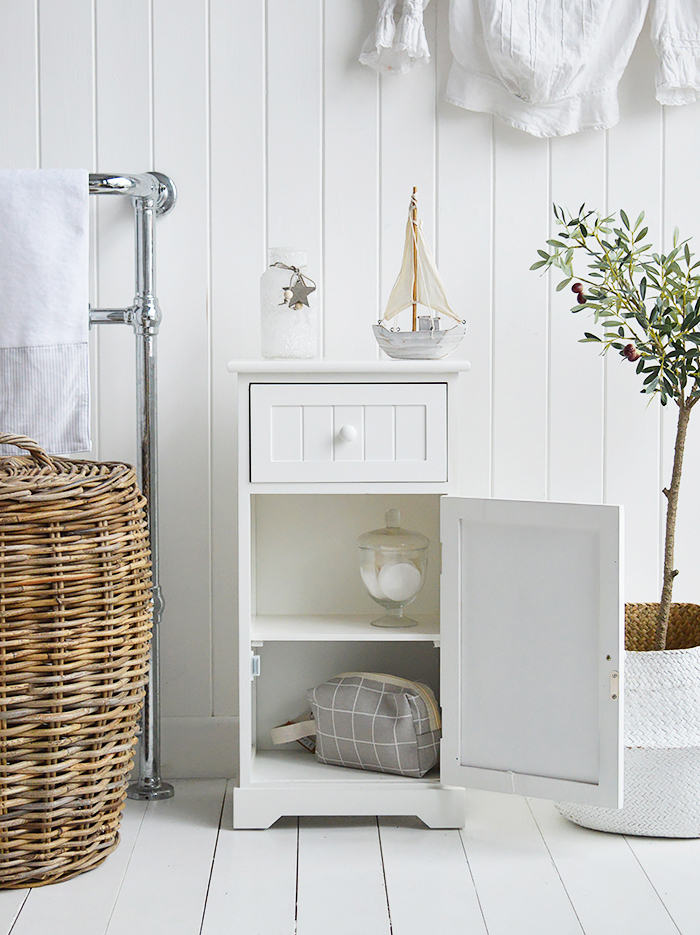 Maine white bathroom cabinet. White Furniture for storage with a cupboard and drawer. Photograph shows the cabinet open for storage