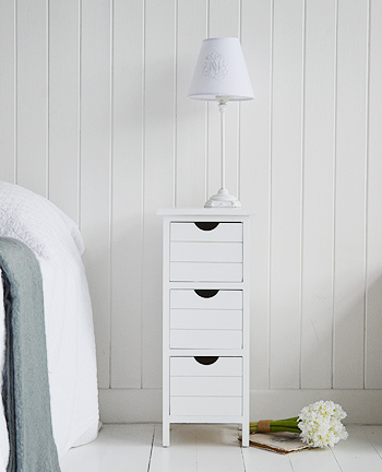 A narrow white bedside table from the Dorset Range with three drawers    Ideal for when space is tight, At only 21cm for the max width, the Dorset slim range offers storage for narrow spaces, with either three or four drawers.    With a white satin painted finish, handless drawers and straight lines, this simple unit is perfect for any room in your home.