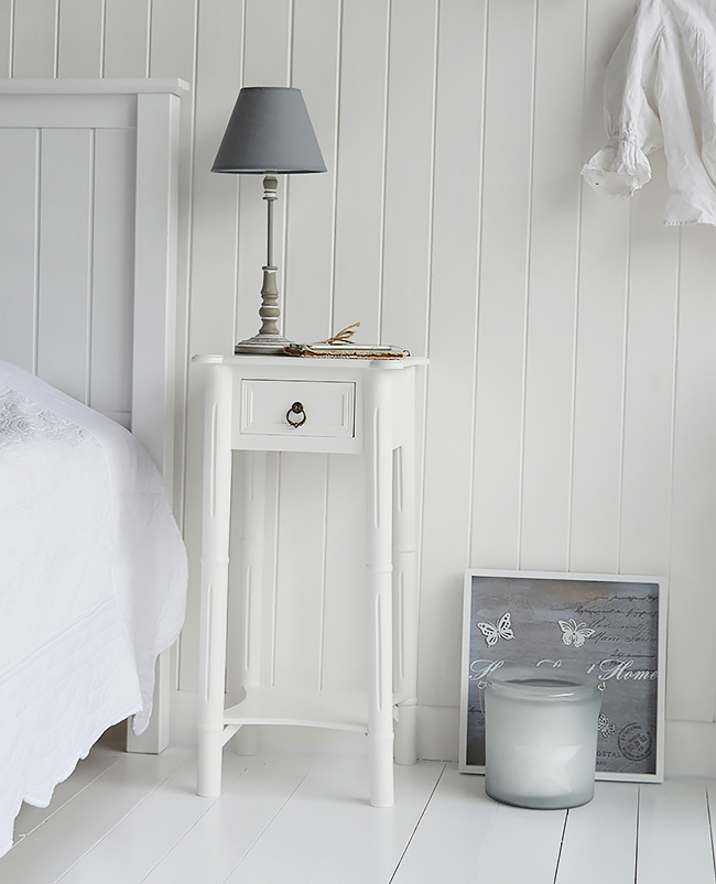 A narrow tall white bedside table with drawer. New England ...